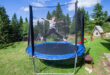 Happy little girl jump on trampoline in backyard. Child fun outd