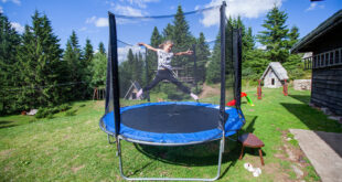Happy little girl jump on trampoline in backyard. Child fun outd